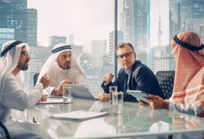 International Business Consultant Advices on Diversification of Investment Portfolio to Successful Arab Company Owners. Multicultural Meeting in Modern Office Between American and Emirati Businessman